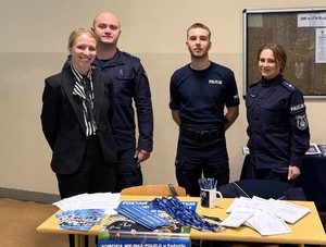 troje policjantów i pracownik Policji na spotkaniu ze studentami przed nimi stolik a na nim ulotki informacyjne