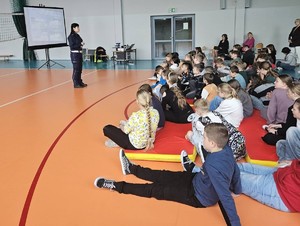 policjantka i uczniowie na sali gimnastycznej w szkole podczas prelekcji