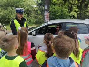 policjantka i grupa uczniów przy kontrolowanym aucie