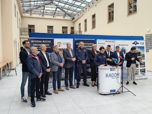 grupa osób podczas konferencji prasowej przy mikrofonie policjantka