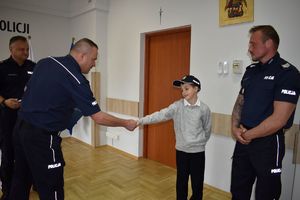 policjant podaje rękę chłopcu obok policjant