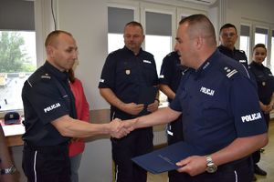 policjant podaje rękę funkcjonariuszowi w tle policjanci