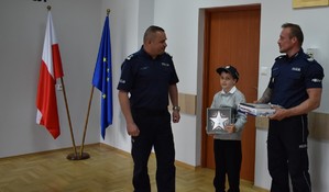 dwaj policjanci i dziecko na świetlicy chłopiec trzyma pudełko