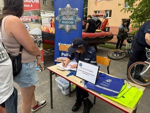 policjantka siedzi przy stoliku coś pisze w tle policjant znakuje rower