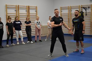 dwaj policjanci strojach sportowych na sali gimnastycznej dookoła pracownice komendy
