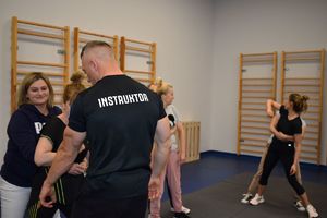 policjant w stroju sportowym pokazuje podstawy samoobrony pracownicom komendy
