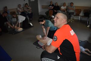 dwaj policjanci  i pracownice podczas szkolenia z pierwszej pomocy ćwiczenia na fantomach