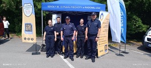 Pięć osób stoi na tle namiotu: dwóch umundurowanych policjantów oraz trzech uczniów ze szkoły ZDZ.