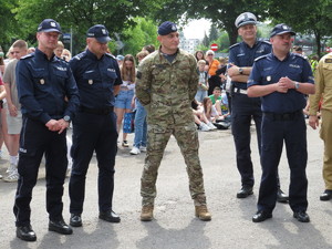 Przedstawiciele policji, umundurowani funkcjonariusze stoją razem, koło sceny podczas oficjalnej części wydarzenia.