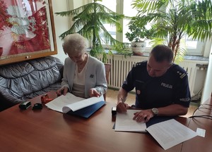 policjant i kobieta siedza przy stole i podpisuja porozumienie