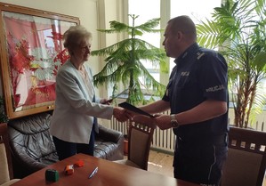 policjant i kobieta podaja sobie dłon i gratuluja podpisania porozumienia o wspólpracy