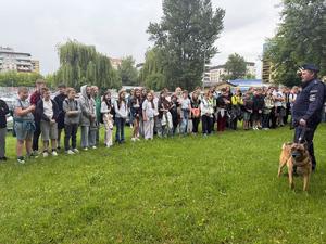 przed budynkiem grupa uczniów i policjant z psem