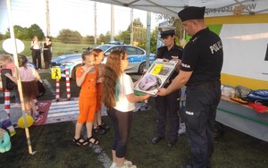 dwoje policjantów przekazuje dzieciom policyjne gadżety