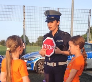 policjantka trzyma znak stop obok 2 dziewczynki
