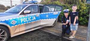 radiowóz obok policjantka i chłopiec