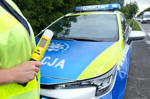 radiowóz i alkomat w dłoni policjanta