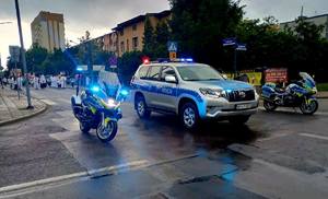 policyjne motocykle oraz radiowóz na ulicy podczas zabezpieczenia procesji