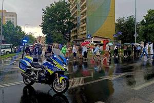 policyjny motocykl na ulicy podczas zabezpieczenia procesji, w tle uczestnicy