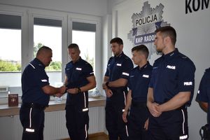 komendant podaje rękę policjantowi gratuluje mu obok 3 policjantów