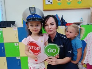 policjantka i dwie dziewczynki jedna  z nich w policyjnej czapce