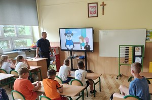 policjant na sali lekcyjnej dzieci siedza w ławkach