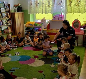 policjantka rozdaje dzieciom w przedszkolu ulotki