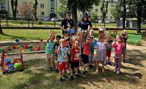 policjantki i grupa przedszkolaków na placu zabaw przed budynkiem przedszkola