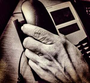 dłoń starszej osoby na słuchawce telefonu