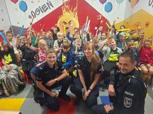 3 policjantów i grupa dzieci trzymająca odblaski