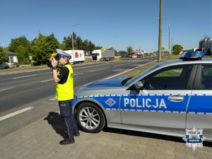 policjantka przy radiowozie na ulicy kontroluje prędkośc