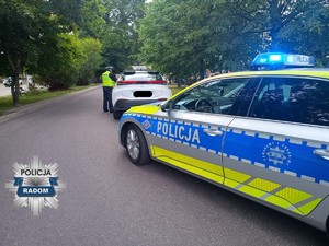 radiowóz a w tle kontrolowany pojazd i policjant
