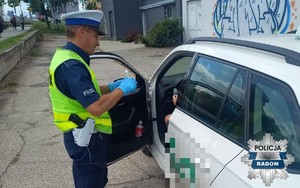 policjant kontroluje kierowce stoi przy aucie