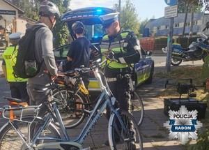 policjanci kontroluja rowerzystów w tle radiowóz