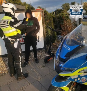 policjant sprawdza trzeźwość mężczyzny po prawej stronie hulajnoga i policyjny motocykl