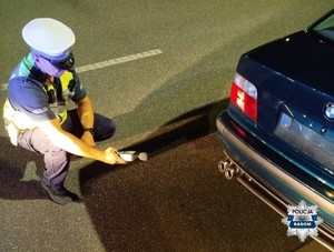 policjant trzyma sonometr i kontroluje pojazd