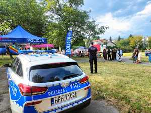 radiowóz a  w tle policjant i uczestnicy festynu