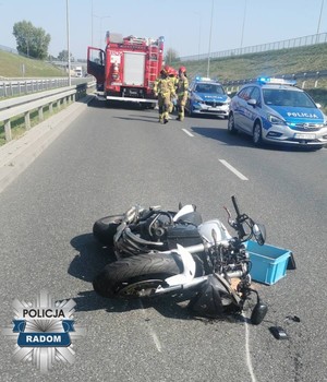 motocykl lezy na jezdni po wypadku  w tle pojazdy służb