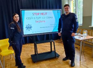 dwoje policjantów przy ekranie z prezentacją napis co czeka hejtera