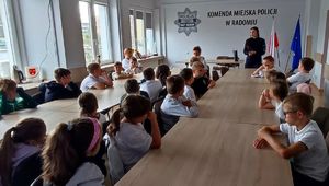 grupa dzieci siedzi na świetlicy w tle policjantka podczas prelekcji