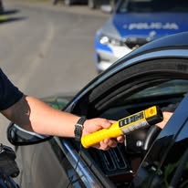 alkomat w dłoni mundurowego przy aucie