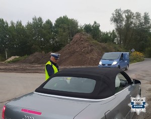 policjant przy aucie w tle niebieski bus