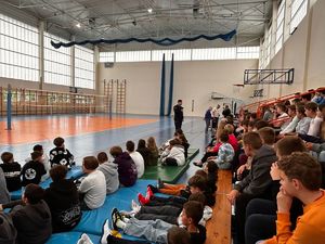 policjant i uczniowie na sali gimnastycznej podczas prelekcji