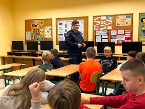 policjant i uczniowie na sali podczas prelekcji