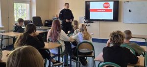 policjant i uczniowie na sali podczas prelekcji