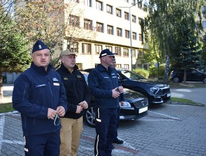 3 policjantów i strażak przed budynkiem komendy