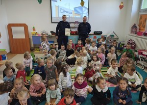 grupa dzieci w tle dwóch policjantów