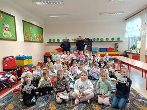 grupa dzieci w sali w tle dwaj policjanci