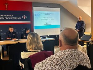 na sali siedza mieszkańcy w tle policjanci i ekran