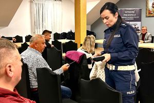 policjantka na sali rozdaje odblaski
