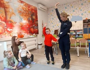 policjantka i dziecko maja uniesiona rękę